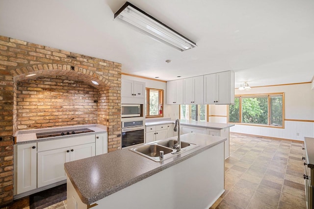 kitchen with sink, a center island with sink, plenty of natural light, appliances with stainless steel finishes, and white cabinets