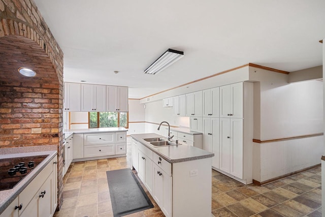 kitchen featuring a kitchen island with sink, sink, and white cabinetry