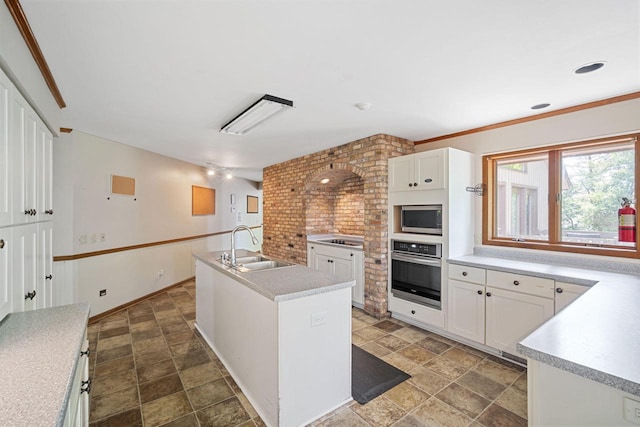 kitchen with white cabinetry, appliances with stainless steel finishes, a kitchen island with sink, and sink