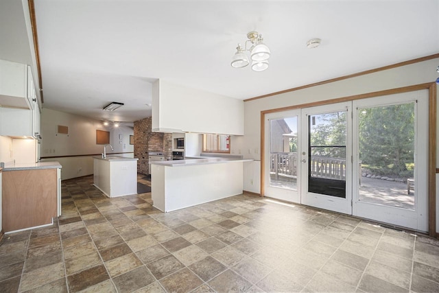 kitchen with sink, an inviting chandelier, a center island, kitchen peninsula, and white cabinets