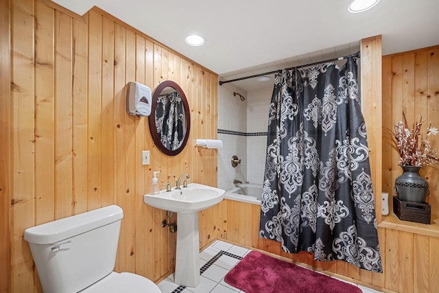 bathroom with wooden walls, shower / bathtub combination with curtain, and toilet