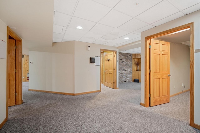 hallway with carpet flooring and a paneled ceiling