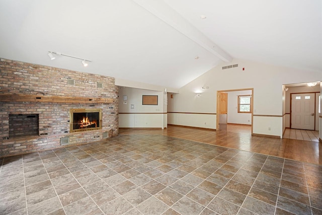 unfurnished living room with rail lighting, beam ceiling, wood-type flooring, high vaulted ceiling, and a fireplace