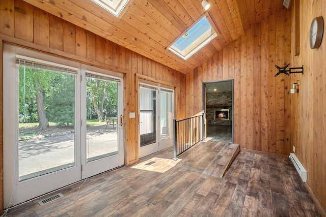 doorway to outside with a skylight, wooden walls, wood-type flooring, a fireplace, and a baseboard radiator