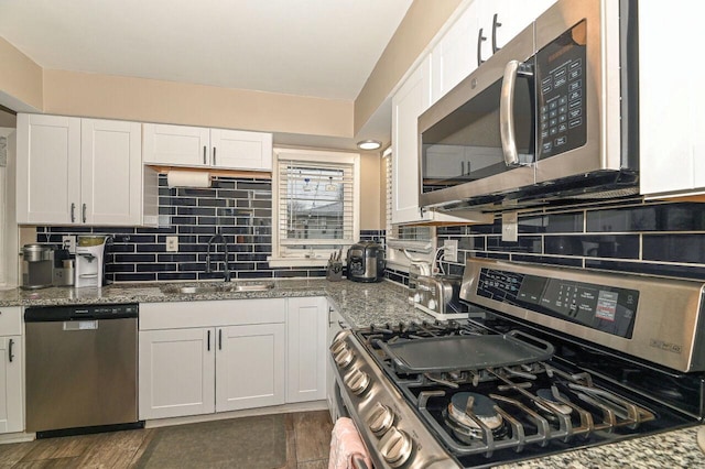 kitchen with sink, white cabinetry, tasteful backsplash, stone countertops, and appliances with stainless steel finishes