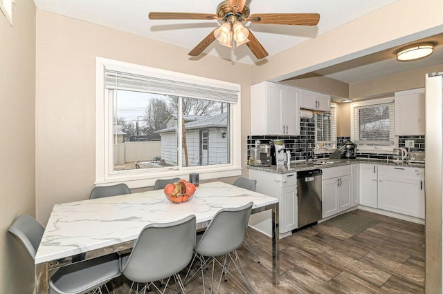 kitchen featuring tasteful backsplash, stainless steel dishwasher, light stone countertops, and white cabinets