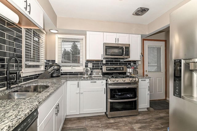 kitchen featuring stone countertops, tasteful backsplash, white cabinetry, sink, and stainless steel appliances