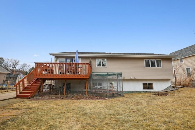 back of house featuring a trampoline, a wooden deck, and a lawn