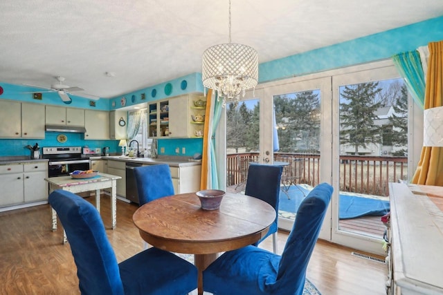 dining area with ceiling fan with notable chandelier, sink, and light hardwood / wood-style floors