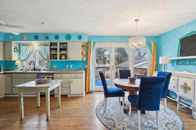 dining area with sink, ceiling fan with notable chandelier, light hardwood / wood-style floors, and a textured ceiling