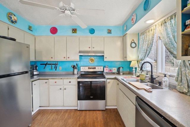 kitchen featuring sink, light hardwood / wood-style flooring, a textured ceiling, appliances with stainless steel finishes, and decorative backsplash