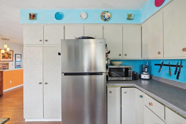 kitchen with appliances with stainless steel finishes, light hardwood / wood-style floors, a textured ceiling, and white cabinets