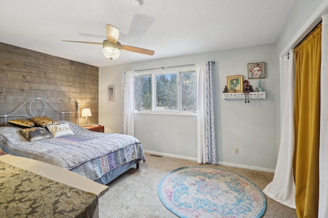 bedroom with light carpet, a textured ceiling, ceiling fan, and wood walls