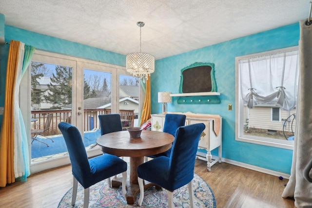 dining area featuring hardwood / wood-style floors, a notable chandelier, french doors, and a textured ceiling