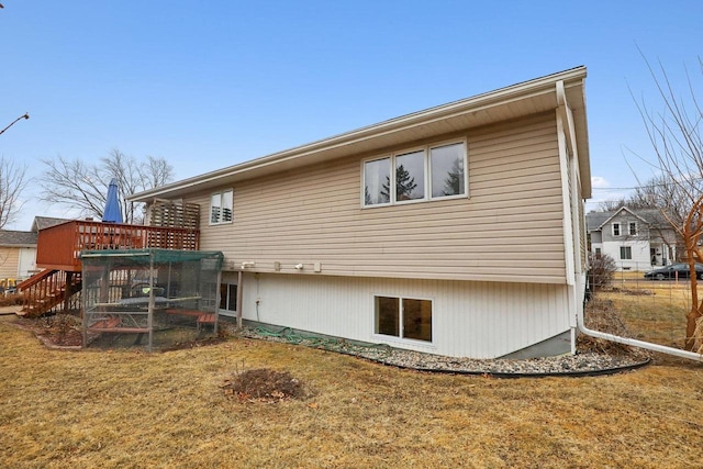 back of property with a wooden deck and a lawn