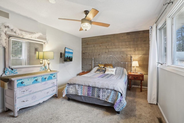 bedroom featuring carpet flooring, a textured ceiling, ceiling fan, and wood walls