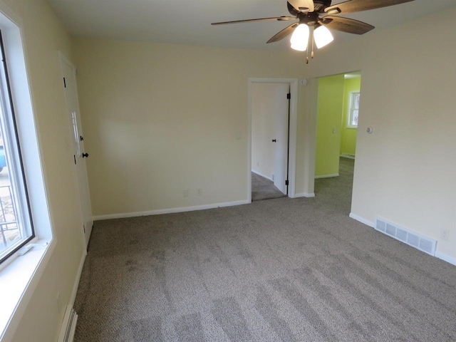 carpeted empty room with ceiling fan and a wealth of natural light