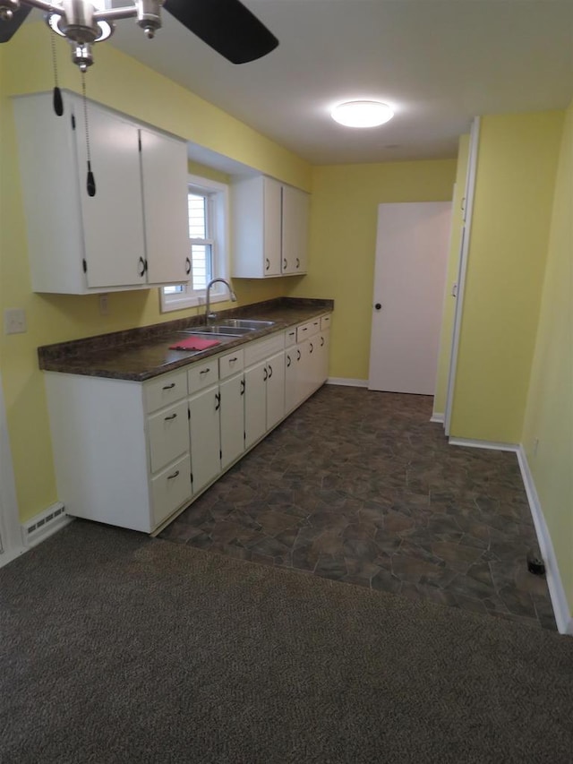 kitchen with white cabinetry, sink, and dark colored carpet