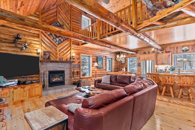 living room with a stone fireplace, high vaulted ceiling, rustic walls, light hardwood / wood-style floors, and wooden ceiling