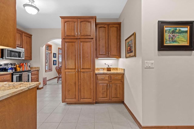 kitchen featuring light stone countertops, light tile patterned floors, and stainless steel appliances