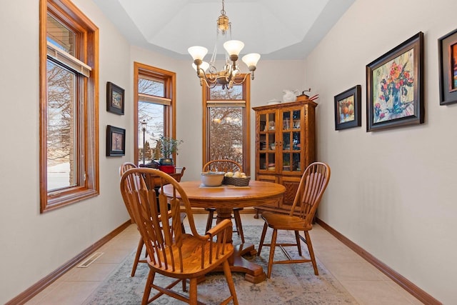 tiled dining room with a chandelier and a raised ceiling