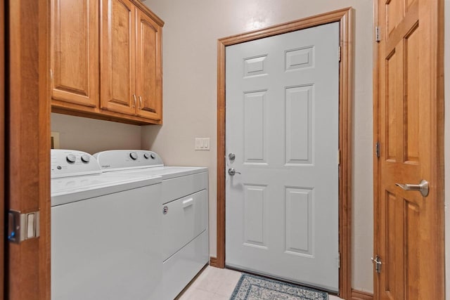 clothes washing area with cabinets, washing machine and dryer, and light tile patterned floors