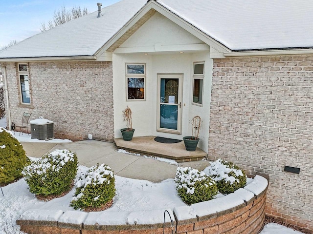 snow covered property entrance featuring central air condition unit