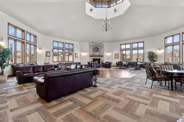 living room with a stone fireplace, carpet flooring, a chandelier, and high vaulted ceiling