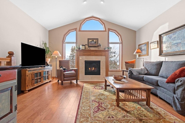 living room with lofted ceiling, hardwood / wood-style flooring, and a tile fireplace