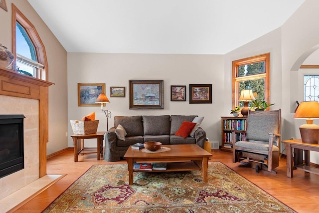 living room featuring a tile fireplace and light wood-type flooring