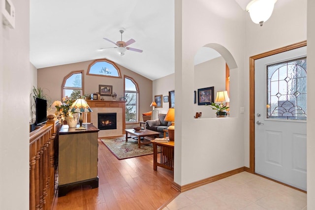 foyer entrance featuring ceiling fan, lofted ceiling, a fireplace, and light hardwood / wood-style floors