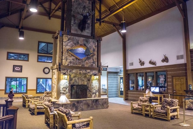 carpeted living room with beamed ceiling, a stone fireplace, wood ceiling, and high vaulted ceiling