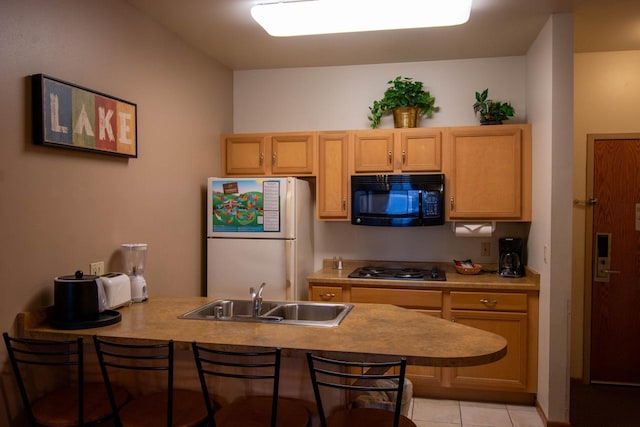 kitchen with sink, light tile patterned floors, light brown cabinetry, and black appliances