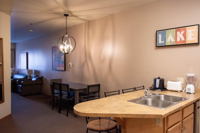 kitchen with a kitchen breakfast bar, sink, hanging light fixtures, and dark colored carpet