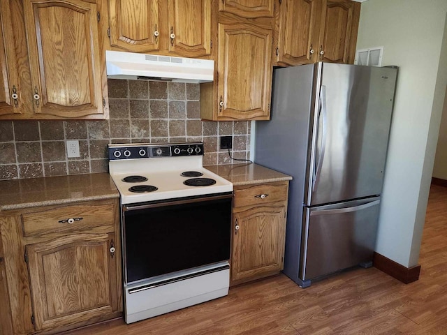 kitchen with stainless steel refrigerator, backsplash, dark hardwood / wood-style flooring, and range with electric stovetop