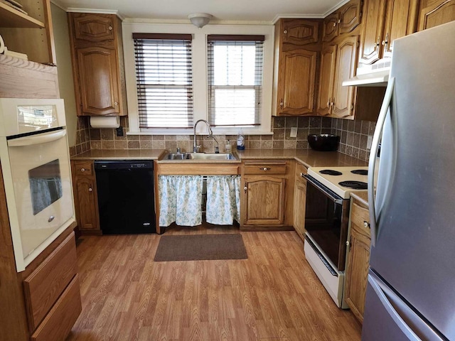 kitchen with sink, backsplash, white appliances, and light hardwood / wood-style floors