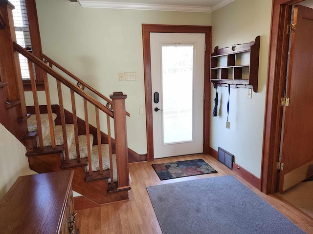 entryway with crown molding, light hardwood / wood-style flooring, and a healthy amount of sunlight