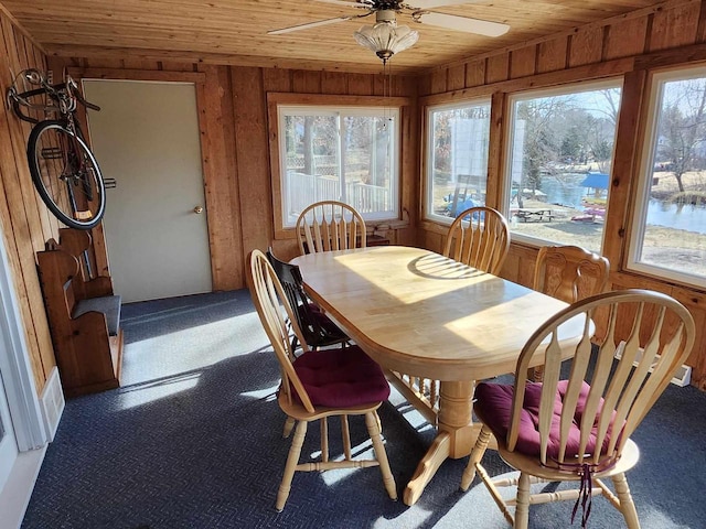 dining area with wood ceiling, plenty of natural light, wooden walls, and carpet floors