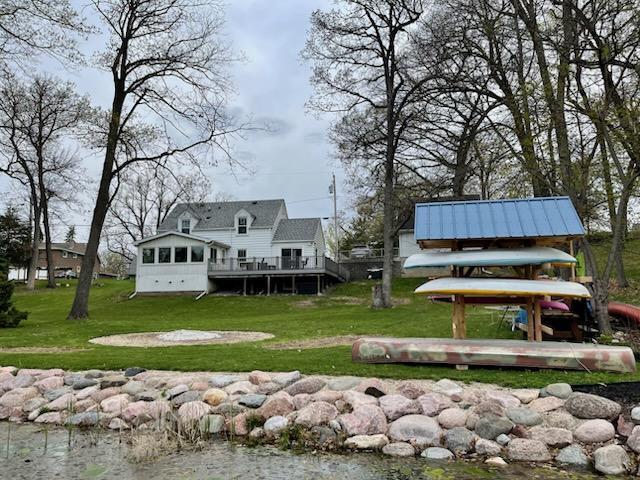 rear view of property featuring a deck and a lawn