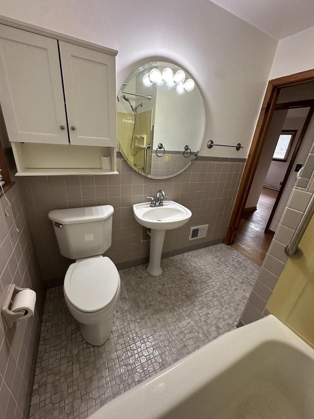 bathroom featuring tile walls, tile patterned flooring, and toilet