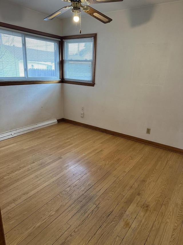 spare room with ceiling fan, light wood-type flooring, and baseboard heating