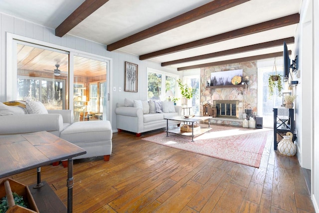 living room with dark hardwood / wood-style flooring, beam ceiling, a stone fireplace, and wood walls