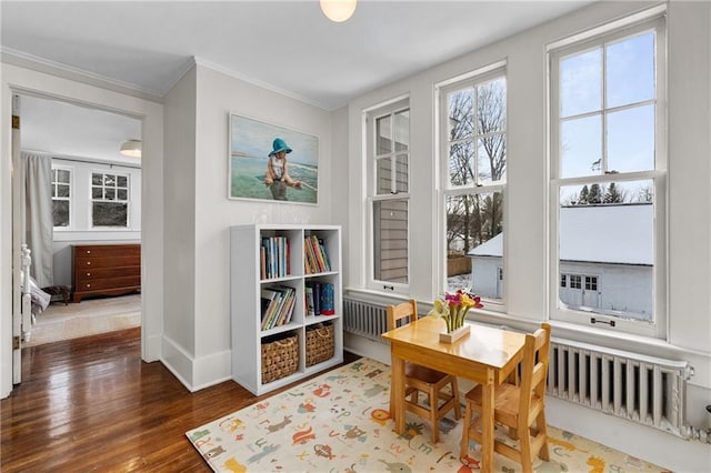 sitting room featuring radiator, crown molding, and dark wood-type flooring