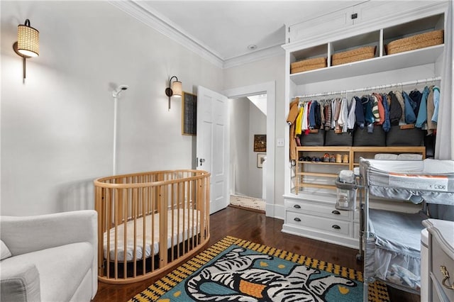 bedroom featuring dark hardwood / wood-style flooring, crown molding, and a nursery area