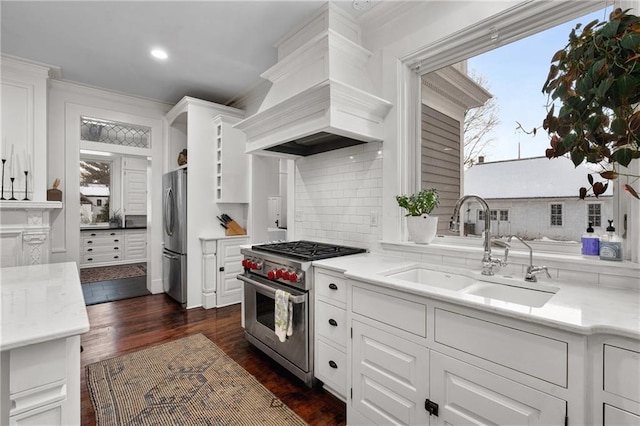 kitchen with premium range hood, white cabinetry, sink, dark hardwood / wood-style flooring, and stainless steel appliances