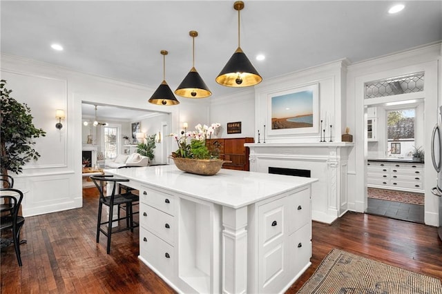 kitchen with white cabinetry, ornamental molding, decorative light fixtures, and a kitchen island