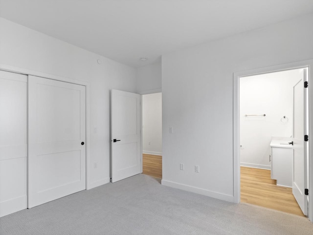 unfurnished bedroom with ensuite bathroom, light carpet, and a closet