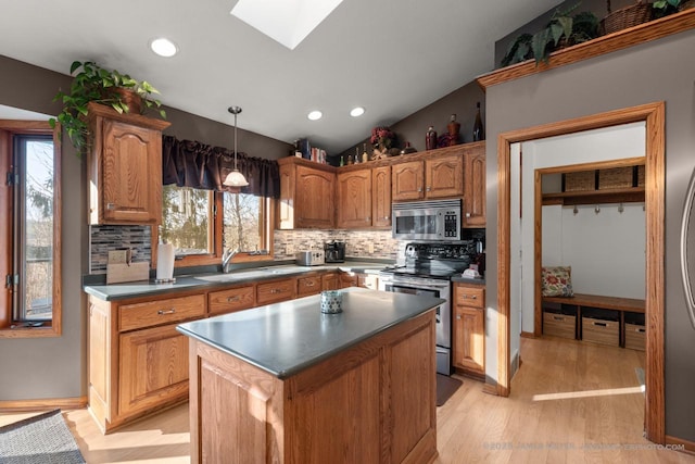 kitchen with sink, appliances with stainless steel finishes, lofted ceiling with skylight, tasteful backsplash, and a kitchen island