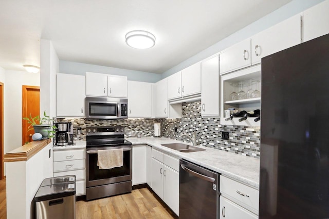 kitchen with stainless steel appliances, white cabinetry, sink, and backsplash