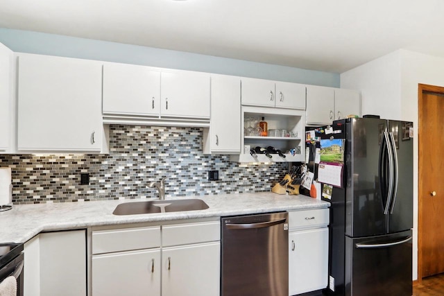 kitchen featuring appliances with stainless steel finishes, sink, white cabinets, backsplash, and light stone counters